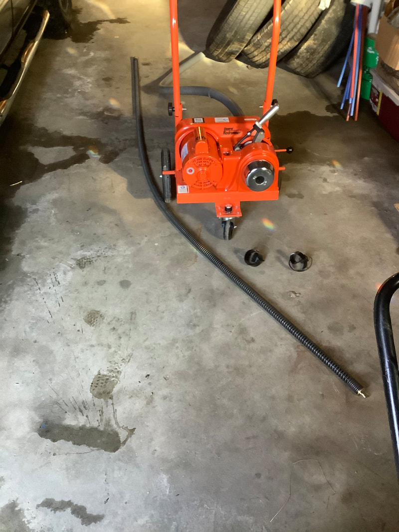 Professional electric drain snake with cable and cutter heads on shop floor