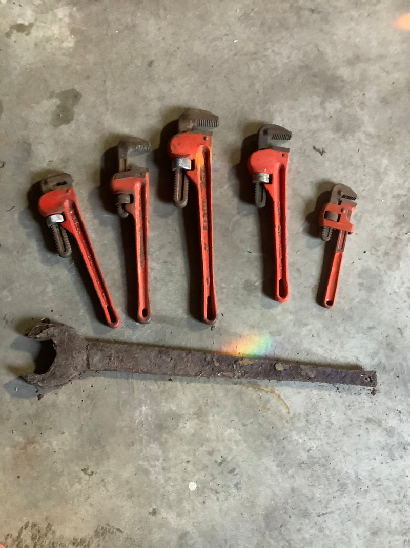 Set of well-used orange pipe wrenches on concrete