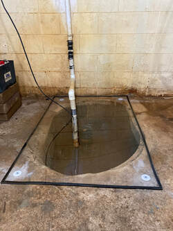 Sealed clear sump basin lid with PVC discharge in a basement